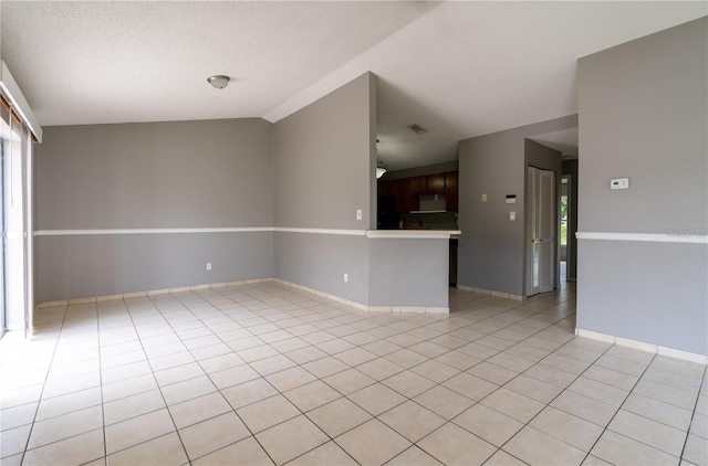 tiled empty room featuring lofted ceiling