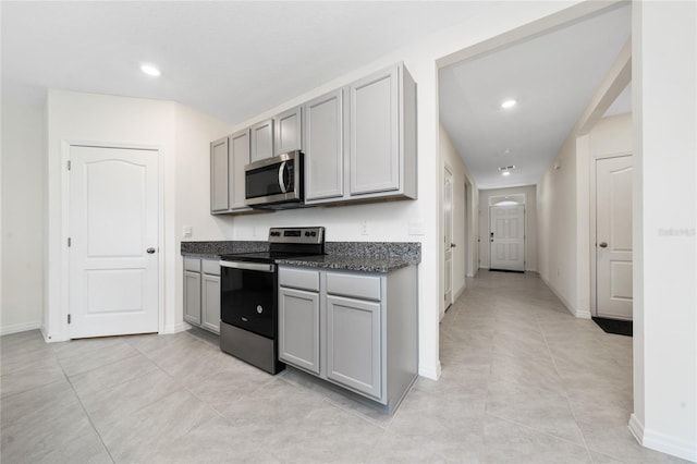 kitchen with gray cabinets, dark stone countertops, light tile patterned floors, and stainless steel appliances