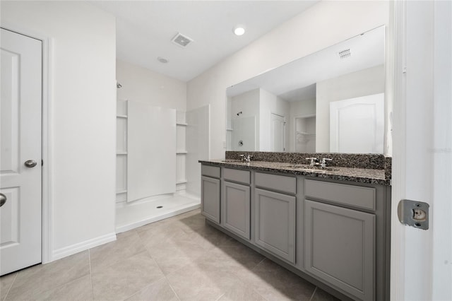 bathroom with a shower, vanity, and tile patterned floors