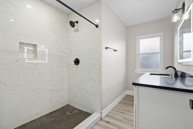 bathroom with vanity, wood-type flooring, and a tile shower