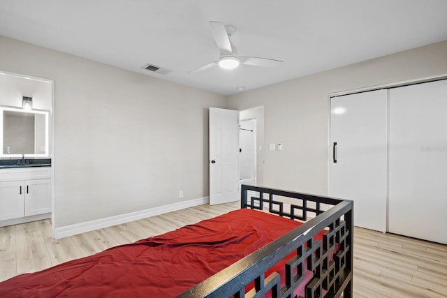 bedroom with sink, ensuite bath, ceiling fan, a closet, and light wood-type flooring