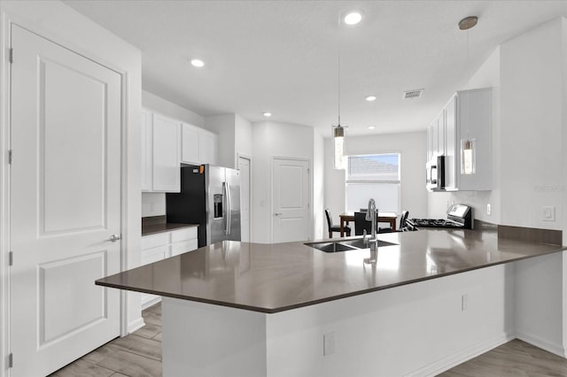 kitchen with kitchen peninsula, appliances with stainless steel finishes, decorative light fixtures, and sink