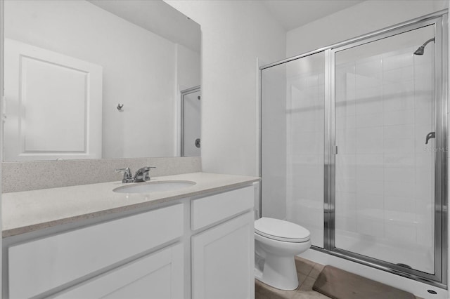 bathroom featuring toilet, vanity, tile patterned floors, and a shower with shower door