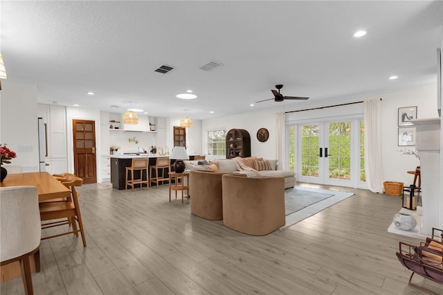 living room with ceiling fan, light hardwood / wood-style flooring, and french doors