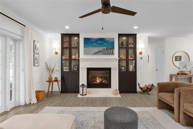 living room with light hardwood / wood-style flooring, ceiling fan, and ornamental molding