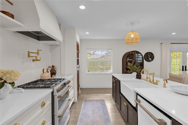 kitchen featuring sink, dishwasher, stainless steel range, pendant lighting, and custom exhaust hood