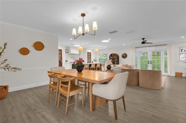 dining room with ceiling fan with notable chandelier, ornamental molding, a textured ceiling, and light hardwood / wood-style flooring