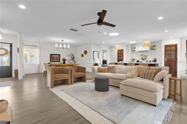 living room featuring light hardwood / wood-style floors and ceiling fan with notable chandelier