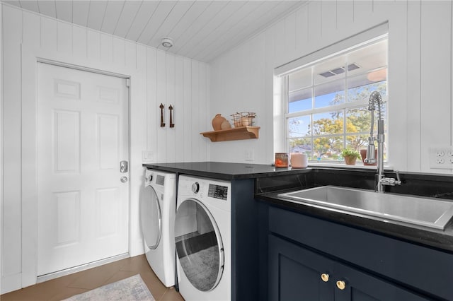 washroom with wood walls, washing machine and dryer, and sink