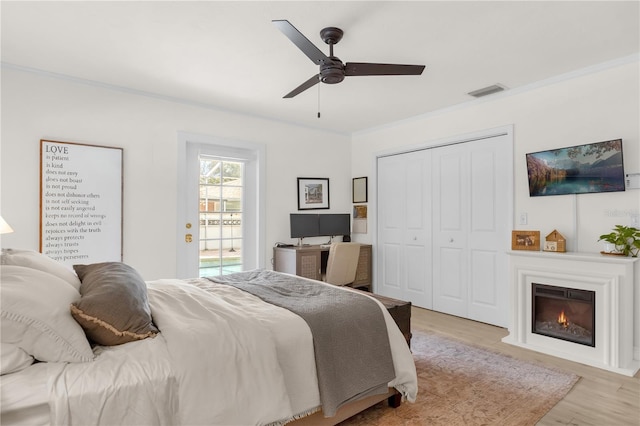 bedroom with access to outside, light hardwood / wood-style flooring, ceiling fan, ornamental molding, and a closet