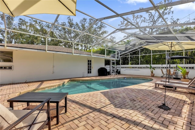 view of pool featuring area for grilling, glass enclosure, and a patio area