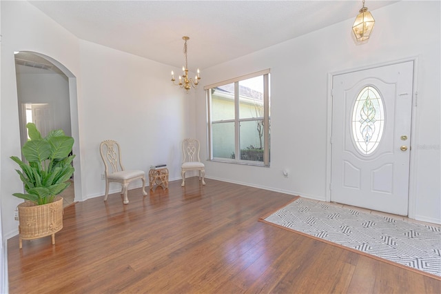 foyer with a wealth of natural light, dark hardwood / wood-style flooring, and a notable chandelier