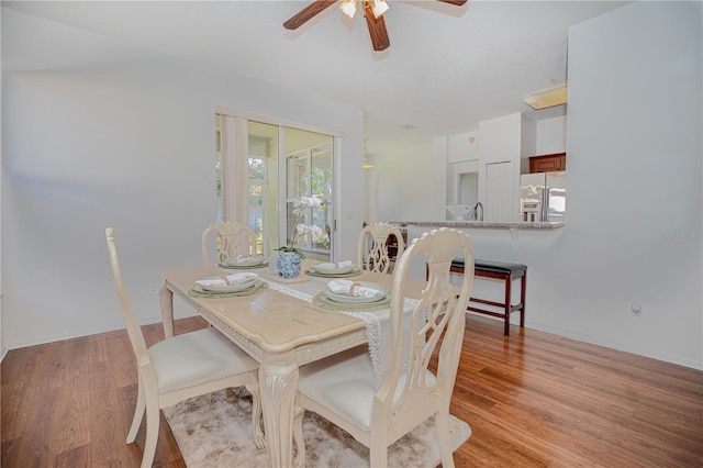 dining room featuring ceiling fan, light wood-type flooring, and sink