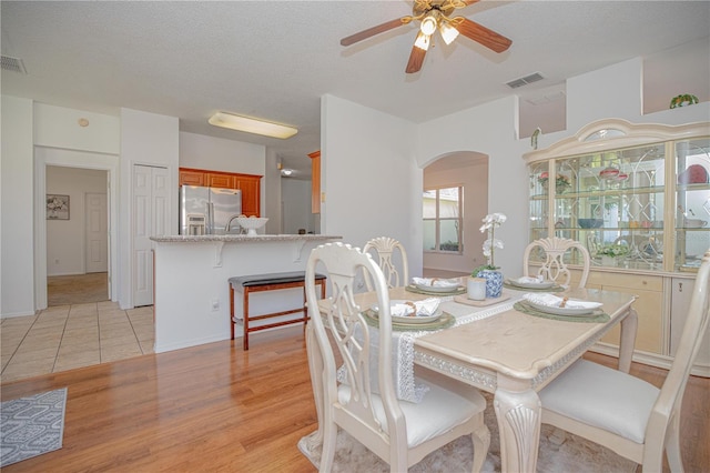 dining area with ceiling fan, a textured ceiling, and light wood-type flooring