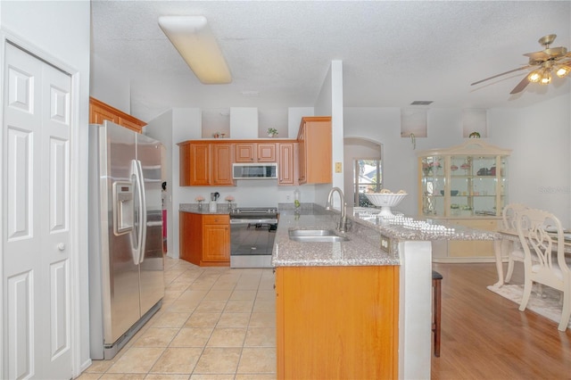 kitchen featuring kitchen peninsula, sink, a breakfast bar area, stainless steel appliances, and light tile patterned floors