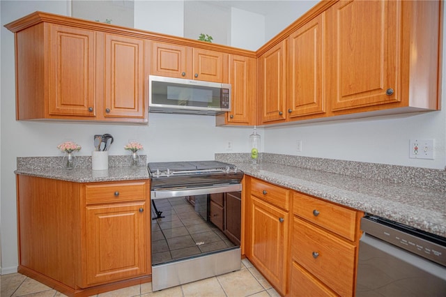 kitchen with light stone counters, light tile patterned floors, and appliances with stainless steel finishes