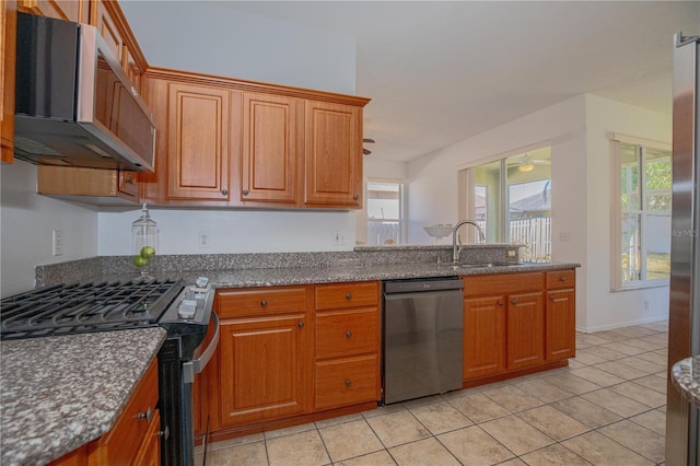 kitchen with light tile patterned floors, sink, dark stone countertops, and stainless steel appliances