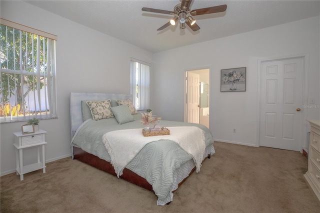 bedroom with ceiling fan, light carpet, and ensuite bath