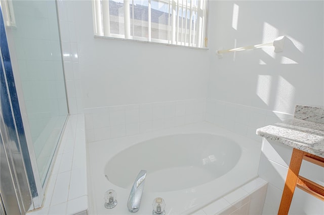 bathroom featuring tiled bath and vanity