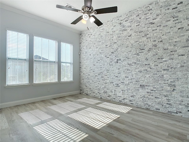 spare room featuring light hardwood / wood-style flooring, a wealth of natural light, ornamental molding, and ceiling fan