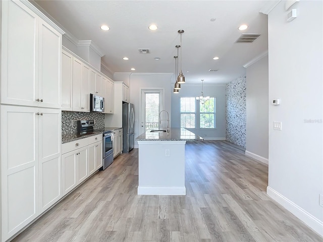 kitchen featuring light hardwood / wood-style floors, pendant lighting, a center island with sink, white cabinets, and appliances with stainless steel finishes