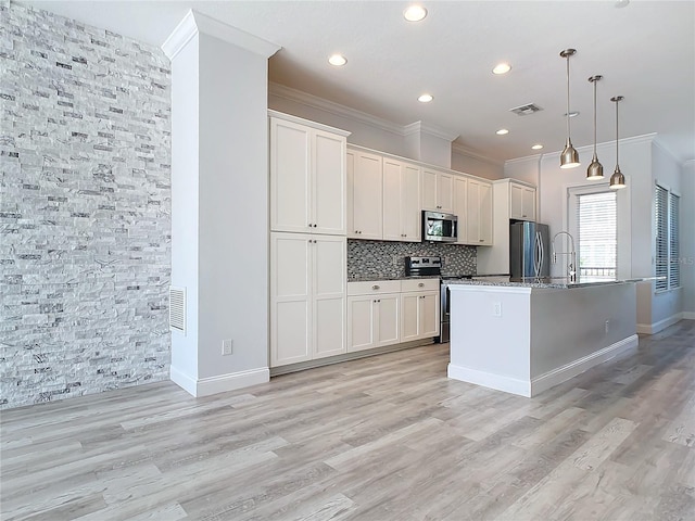 kitchen featuring white cabinets, pendant lighting, an island with sink, and stainless steel appliances