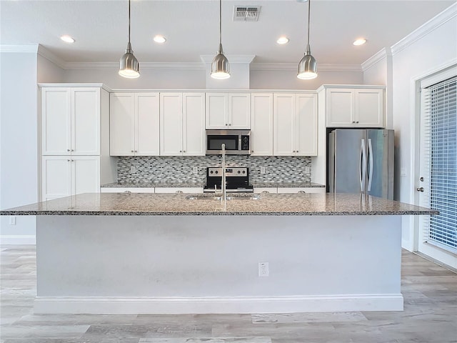 kitchen with dark stone countertops, an island with sink, white cabinets, and stainless steel appliances