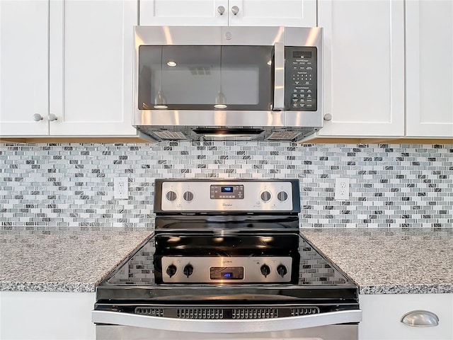 kitchen with decorative backsplash, stainless steel appliances, white cabinetry, and light stone counters