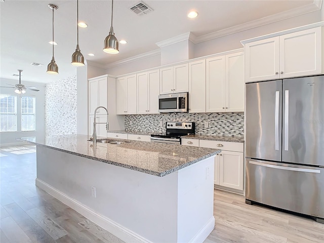 kitchen with appliances with stainless steel finishes, light stone counters, sink, decorative light fixtures, and white cabinets