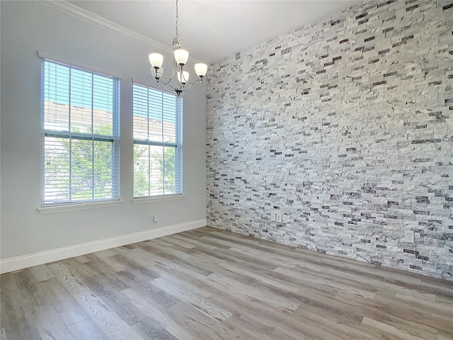 unfurnished room featuring light hardwood / wood-style flooring, ornamental molding, and an inviting chandelier