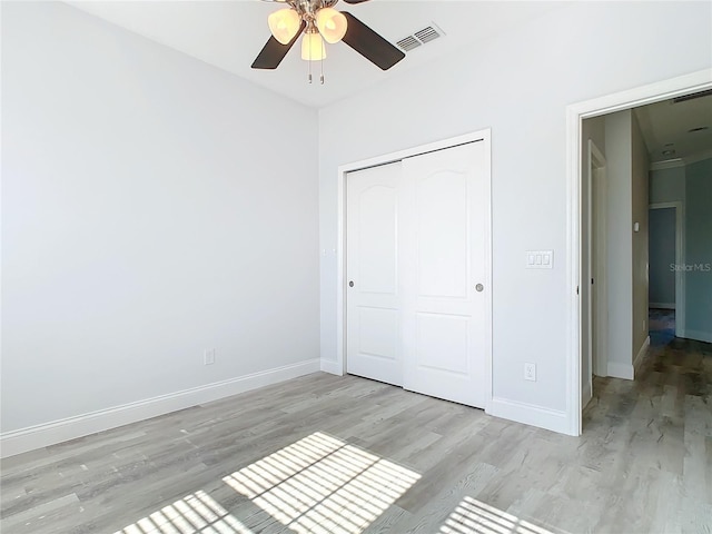 unfurnished bedroom featuring ceiling fan, light hardwood / wood-style floors, and a closet