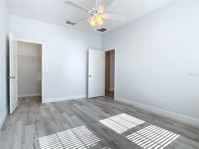 unfurnished bedroom with ceiling fan, light wood-type flooring, and a closet