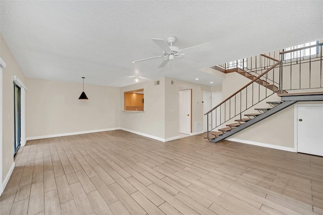 unfurnished living room with a textured ceiling, ceiling fan, and light wood-type flooring