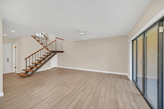 unfurnished living room with a textured ceiling, ceiling fan, and light wood-type flooring