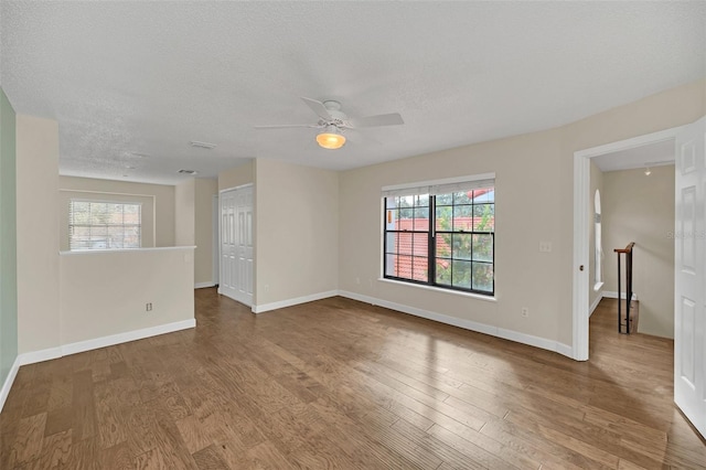 unfurnished room featuring hardwood / wood-style flooring, a wealth of natural light, a textured ceiling, and ceiling fan