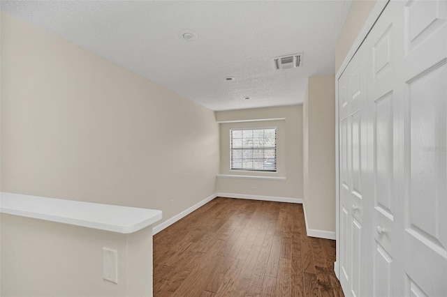 unfurnished room with dark hardwood / wood-style floors and a textured ceiling