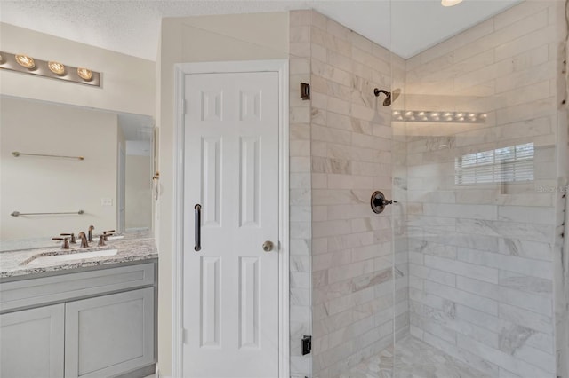 bathroom featuring vanity, a textured ceiling, and a shower with shower door