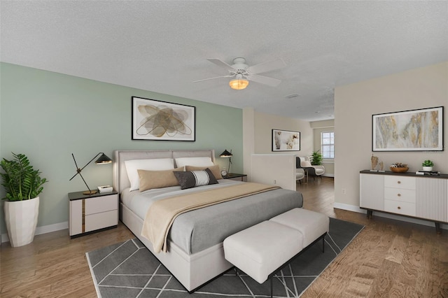 bedroom featuring dark wood-type flooring, a textured ceiling, and ceiling fan