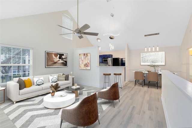 living room with ceiling fan, high vaulted ceiling, and light hardwood / wood-style floors