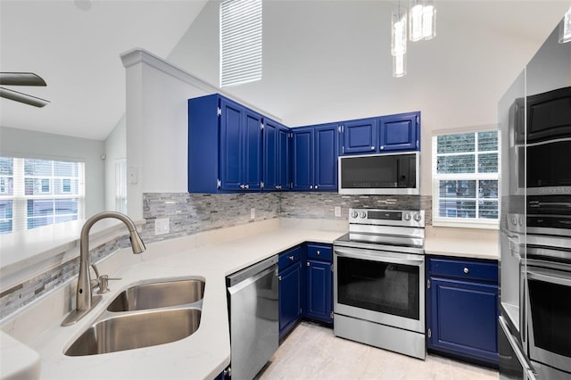 kitchen featuring blue cabinets, hanging light fixtures, sink, vaulted ceiling, and appliances with stainless steel finishes