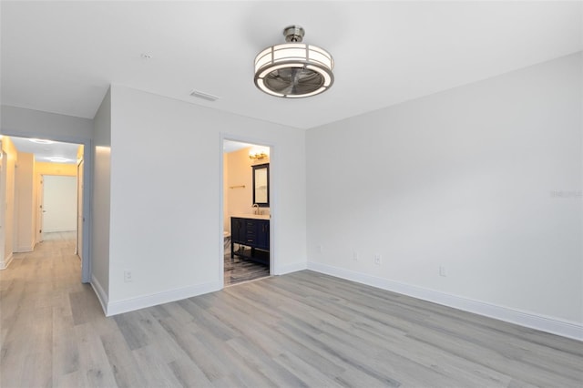 unfurnished bedroom featuring light wood-type flooring and connected bathroom