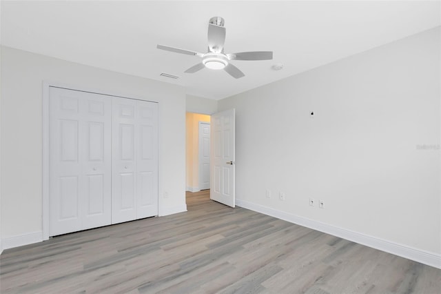 unfurnished bedroom featuring ceiling fan, a closet, and light hardwood / wood-style flooring