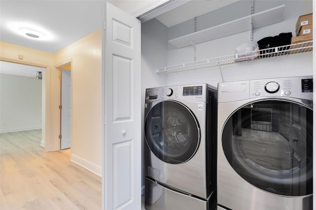 laundry room with washer and clothes dryer and light hardwood / wood-style flooring