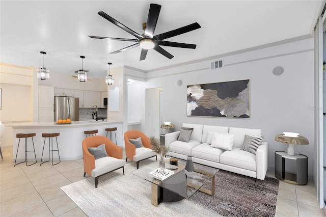 tiled living room featuring ceiling fan with notable chandelier and sink