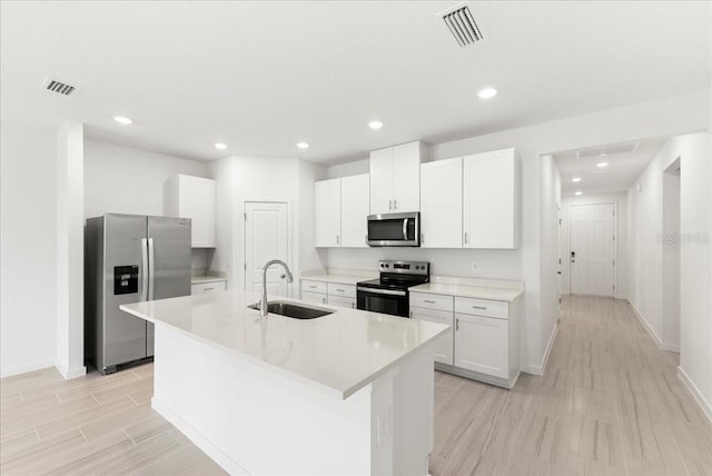 kitchen featuring visible vents, baseboards, white cabinets, a sink, and appliances with stainless steel finishes