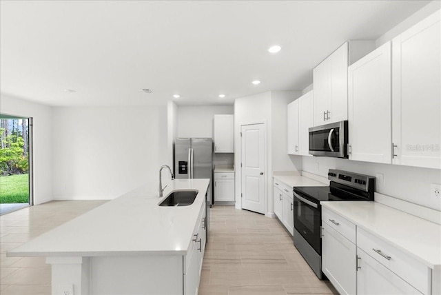 kitchen featuring a center island with sink, recessed lighting, white cabinetry, a sink, and appliances with stainless steel finishes