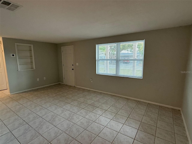 empty room with built in shelves and light tile patterned floors