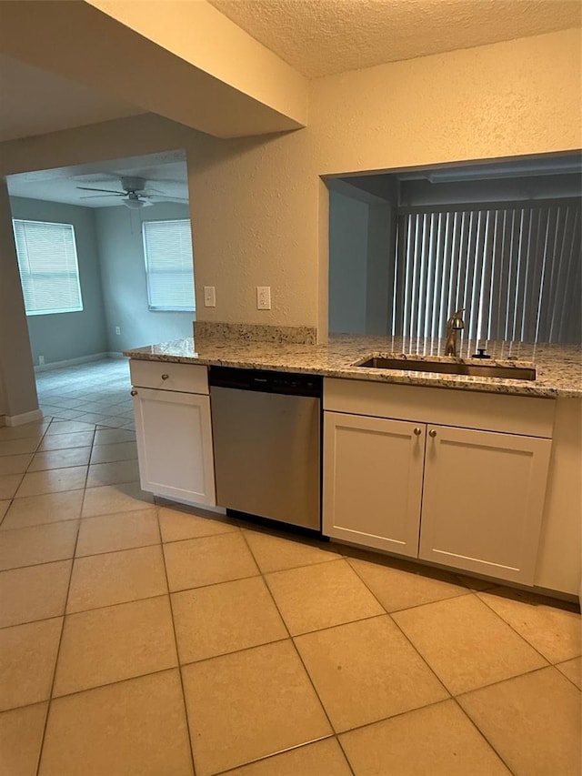 kitchen featuring light stone counters, stainless steel dishwasher, and sink