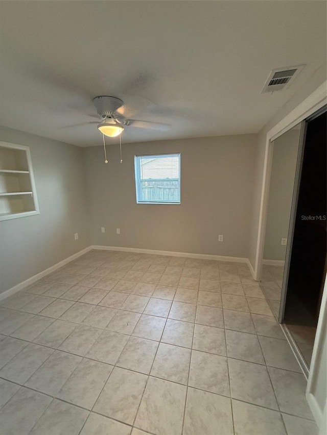 tiled spare room with built in shelves and ceiling fan