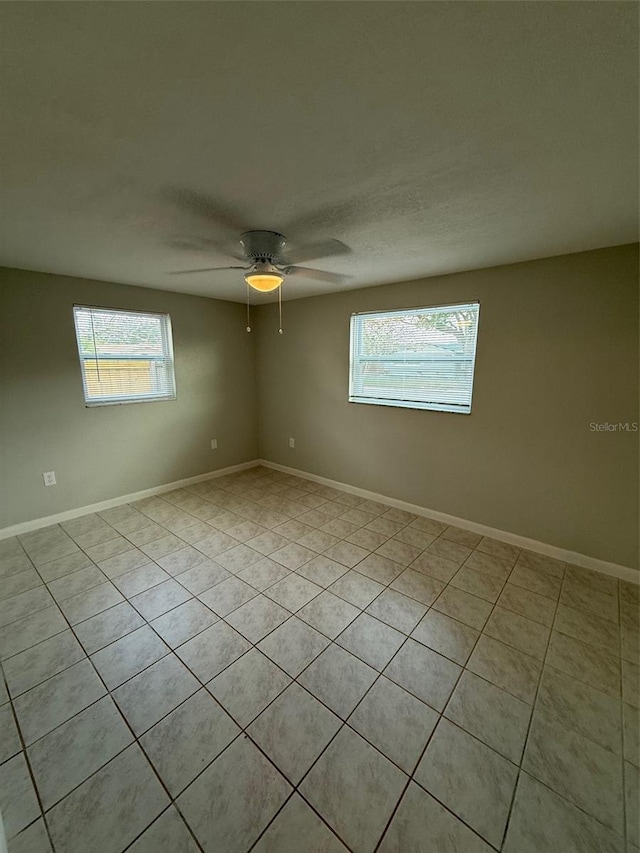 spare room featuring ceiling fan, a healthy amount of sunlight, and light tile patterned flooring